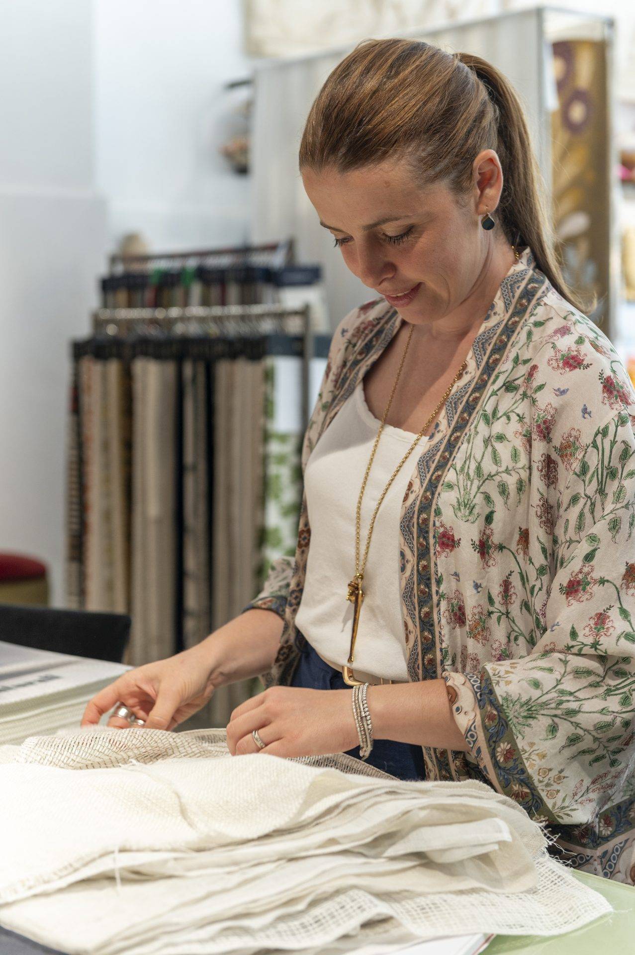 Mani che lavorano un tessuto di lino sul tavolo dell'atelier Zefiro Interiors a Empoli