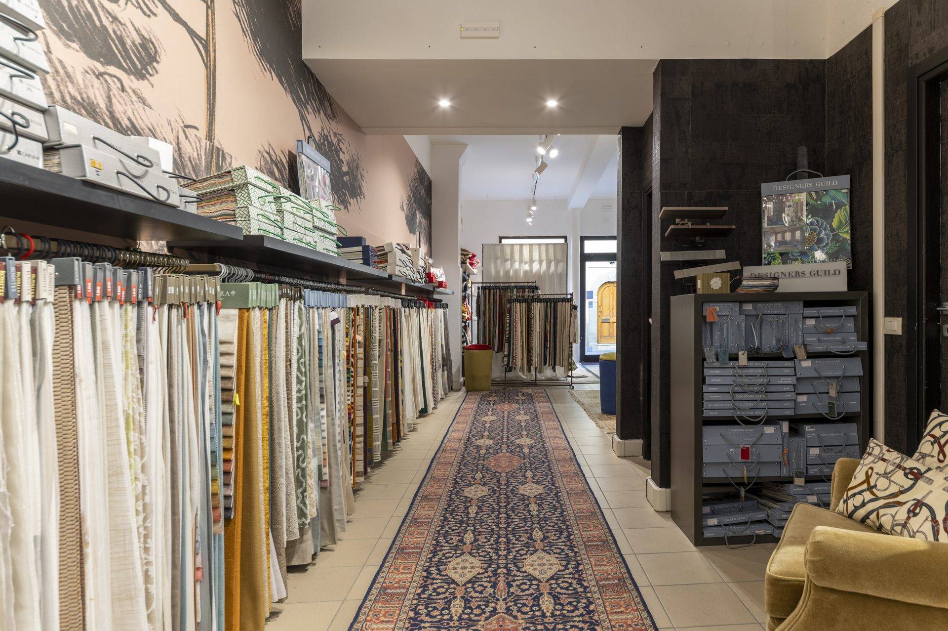 Corridoio dei campionari di tessuti d'arredamento nell'atelier Zefiro Interiors a Empoli, con tappeto runner persiano