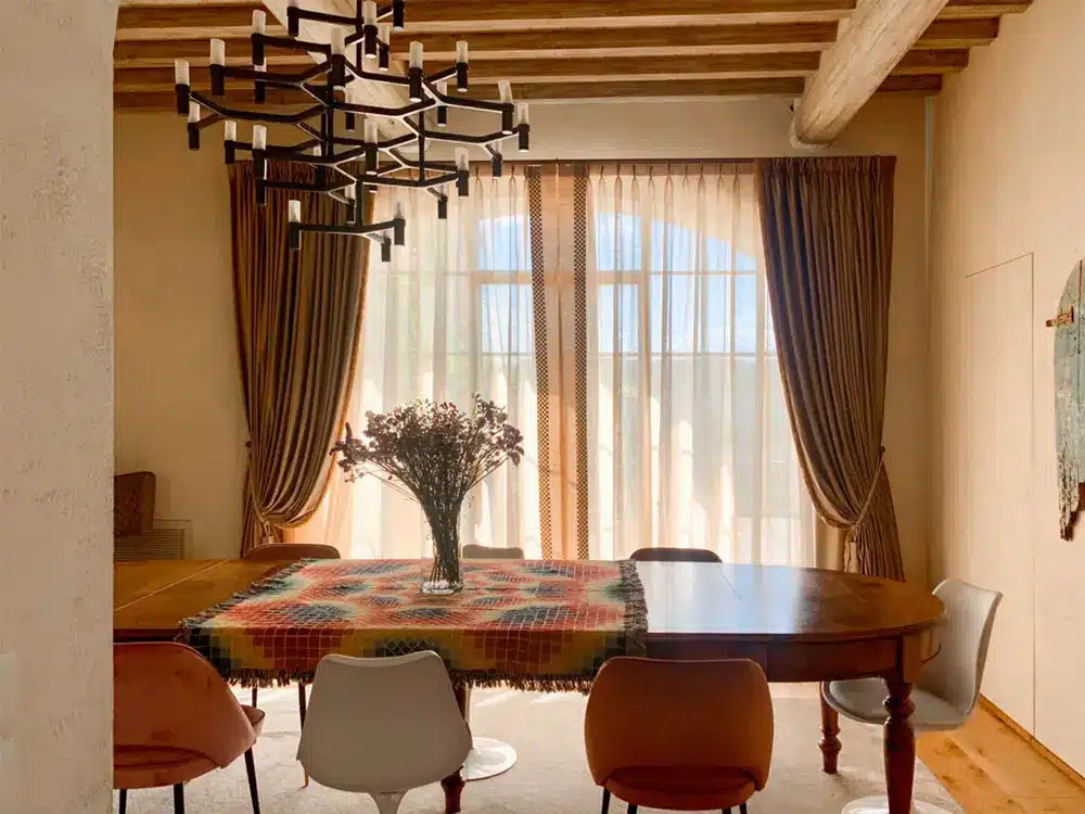 The dining room where double curtains have been installed to frame the large windows