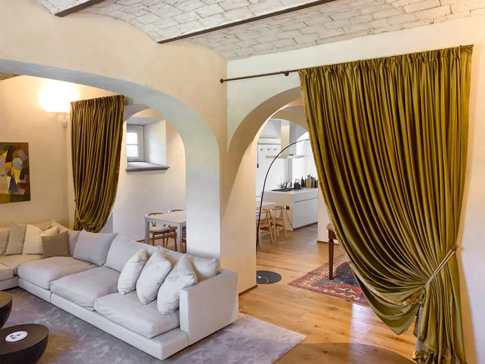 Progettazione di interni a Firenze per un casala in collina con installazione di tende Dedar a dividere la zona living open space